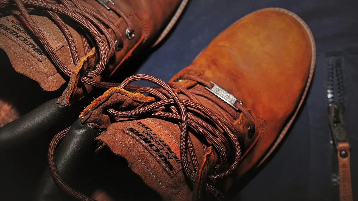 A pair of brown leather boots with laces and a zipper on a dark blue surface.